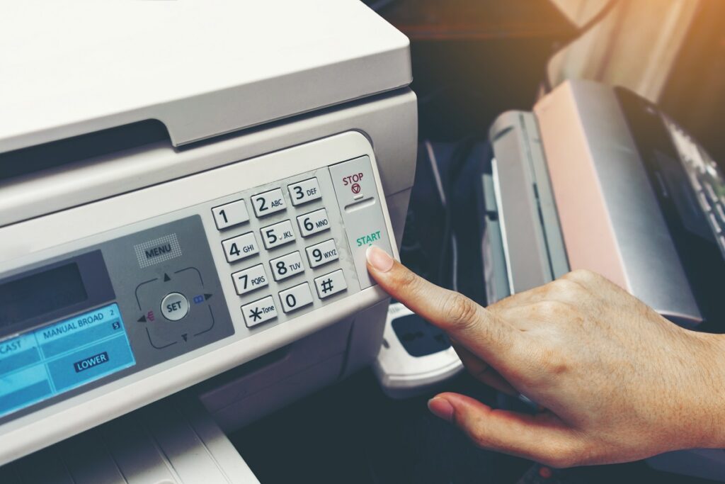 Finger pressing start button of fax machine