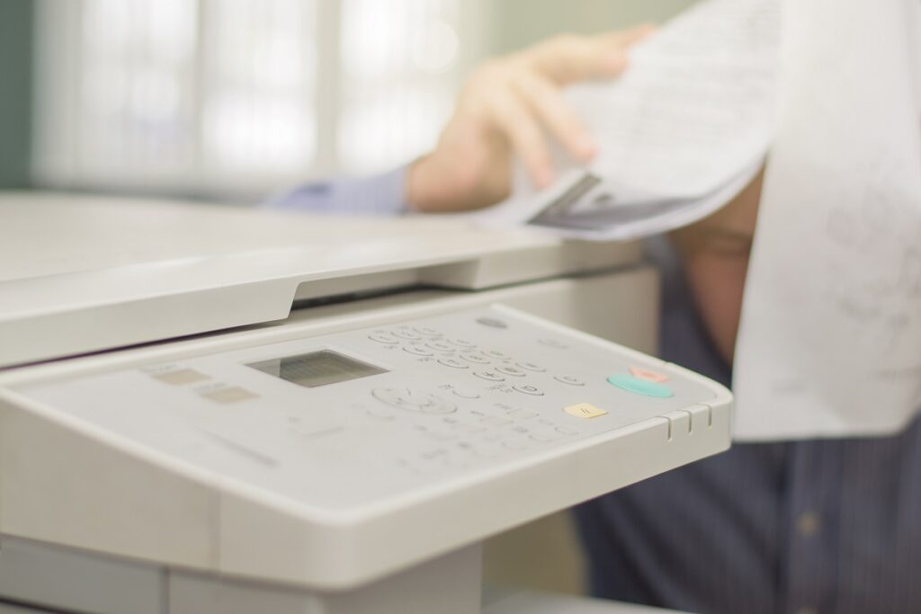 A man having a problem with a fax and copy machine at work 