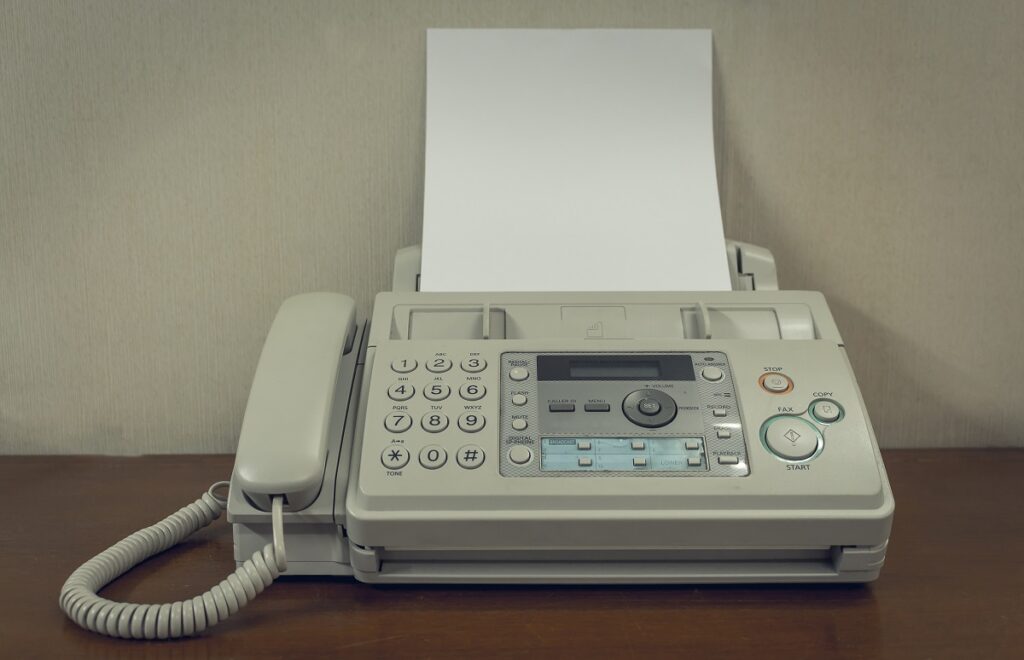 An old fax machine with an empty sheet of paper