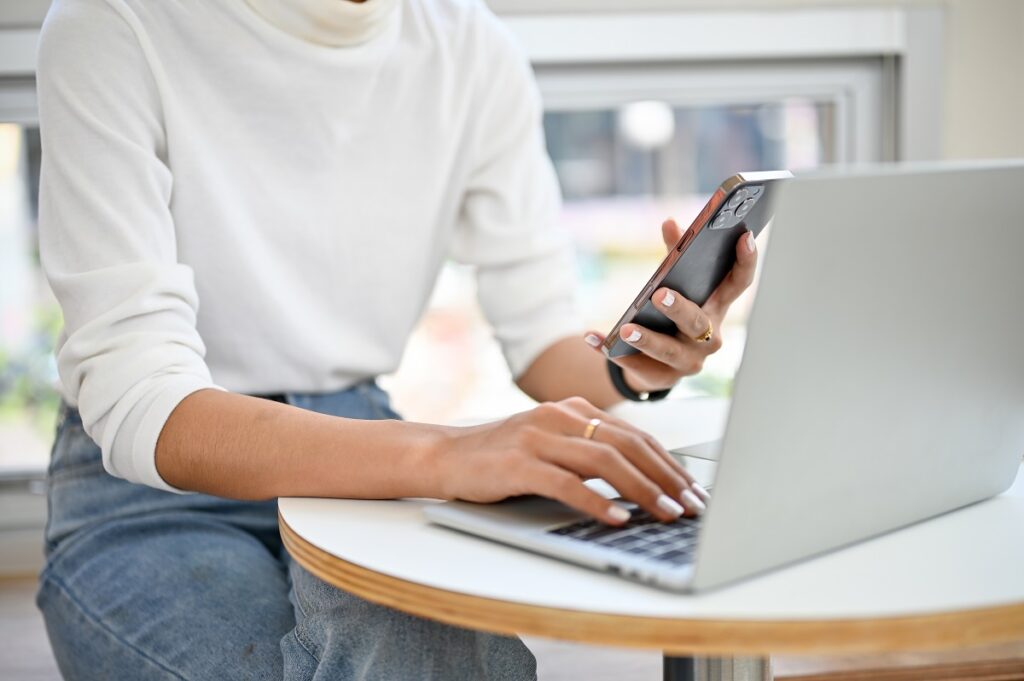 A woman using a smartphone and a laptop to fax without a fax machine 